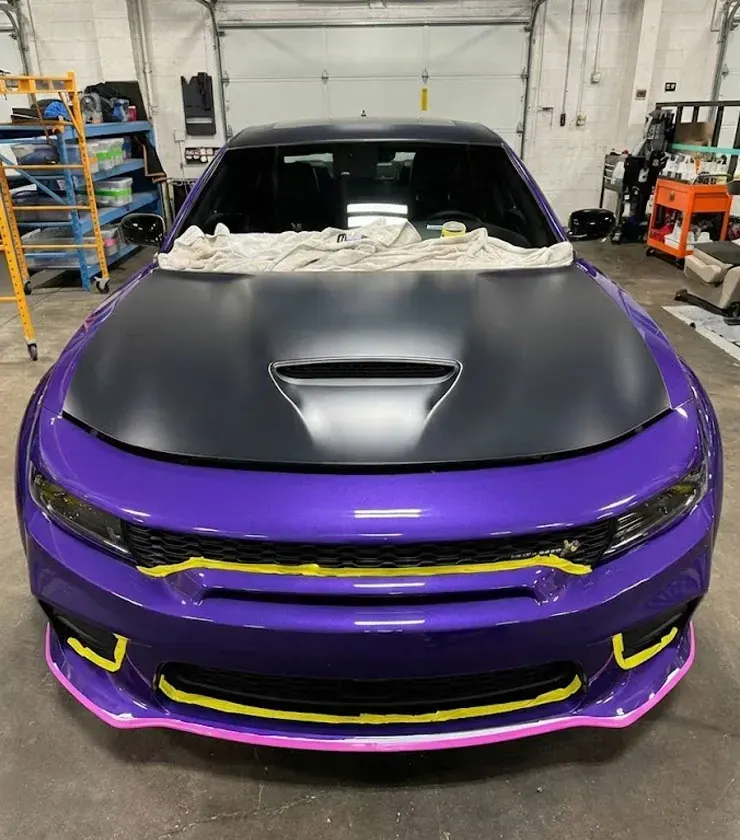Purple Dodge Charger with a matte black hood, panel edges masked during prep